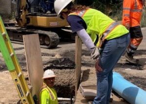 Workers installing water main in street.