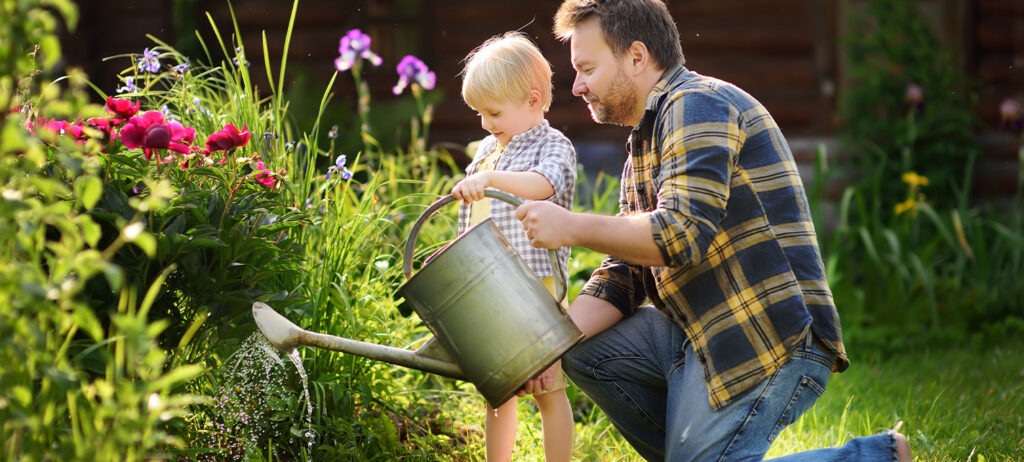 Photo of child and parent watering plants