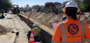 Female Cal Water worker watching another male Cal Water worker installing a new water main in Selma.