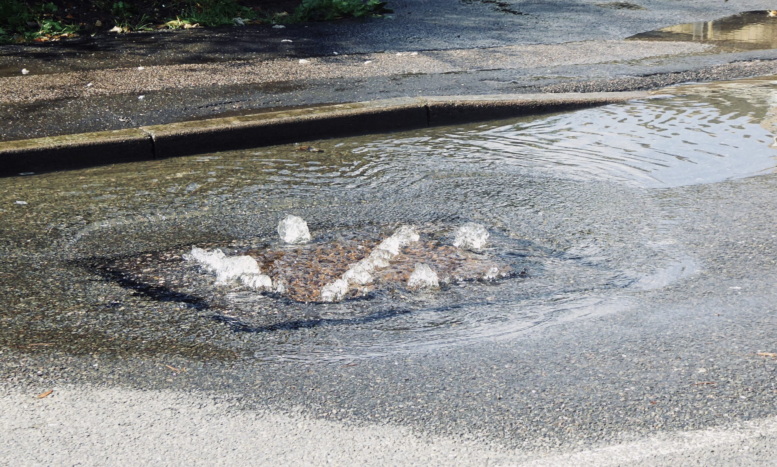 Water bubbling up out of a drain onto the street
